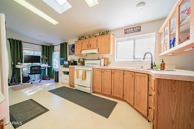 a kitchen with stainless steel appliances granite countertop a stove top oven a sink dishwasher and white cabinets with wooden floor