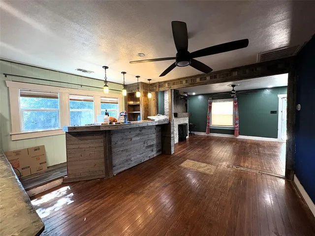 a kitchen with stainless steel appliances kitchen island granite countertop a refrigerator a stove and a wooden floors
