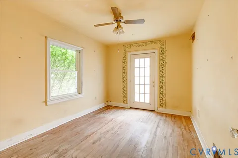 a view of empty room with wooden floor and fan