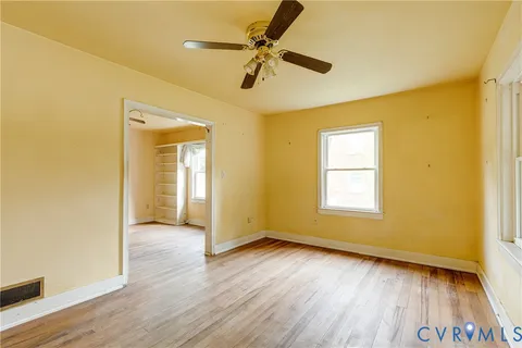 a view of an empty room with a window and wooden floor