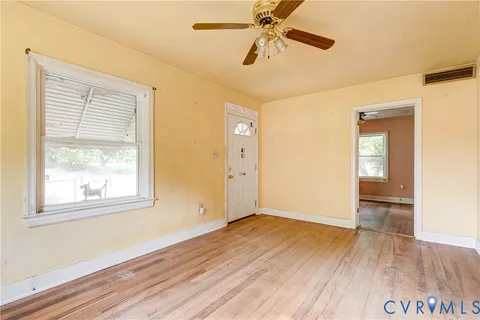 a view of an empty room with wooden floor and a window