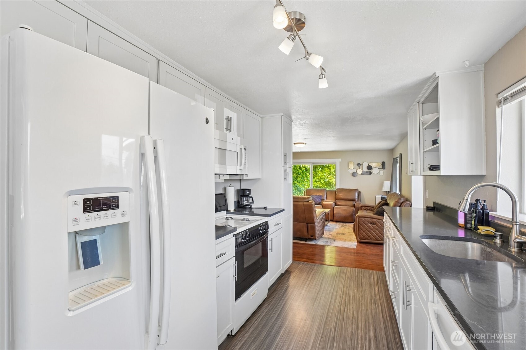 9810 Northeast 3rd Street Vancouver, WA 98664 - Photo 25 of 40 a kitchen with stainless steel appliances a stove a sink a refrigerator white cabinets and couches with wooden floor