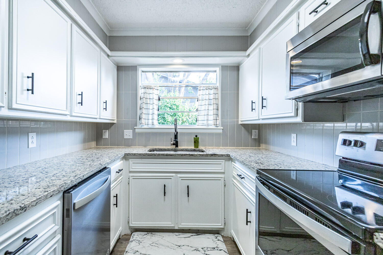 9611 Bangor Avenue Lubbock, TX 79424 - Photo 8 of 29 a kitchen with stainless steel appliances granite countertop a sink dishwasher a stove and a microwave oven with cabinets