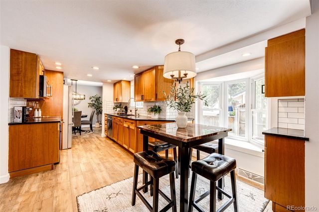 a kitchen with stainless steel appliances a table chairs refrigerator and sink