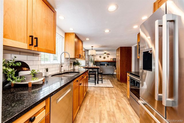 a kitchen with stainless steel appliances granite countertop sink stove refrigerator and cabinets