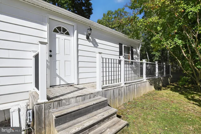 a view of a white house with a large window and wooden fence