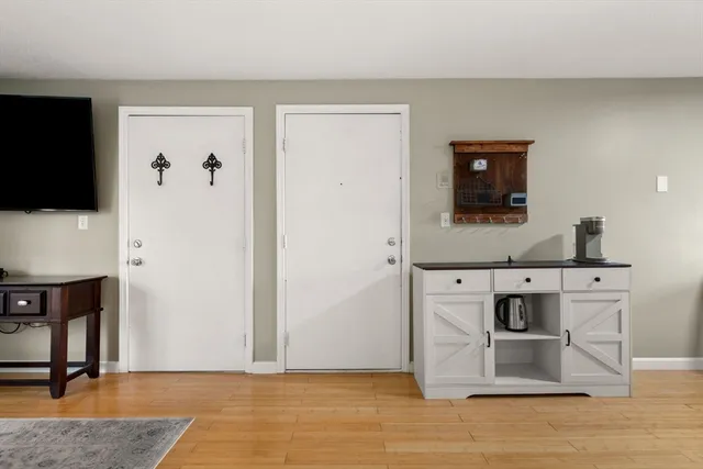 a view of kitchen with stainless steel appliances wooden floor and chair