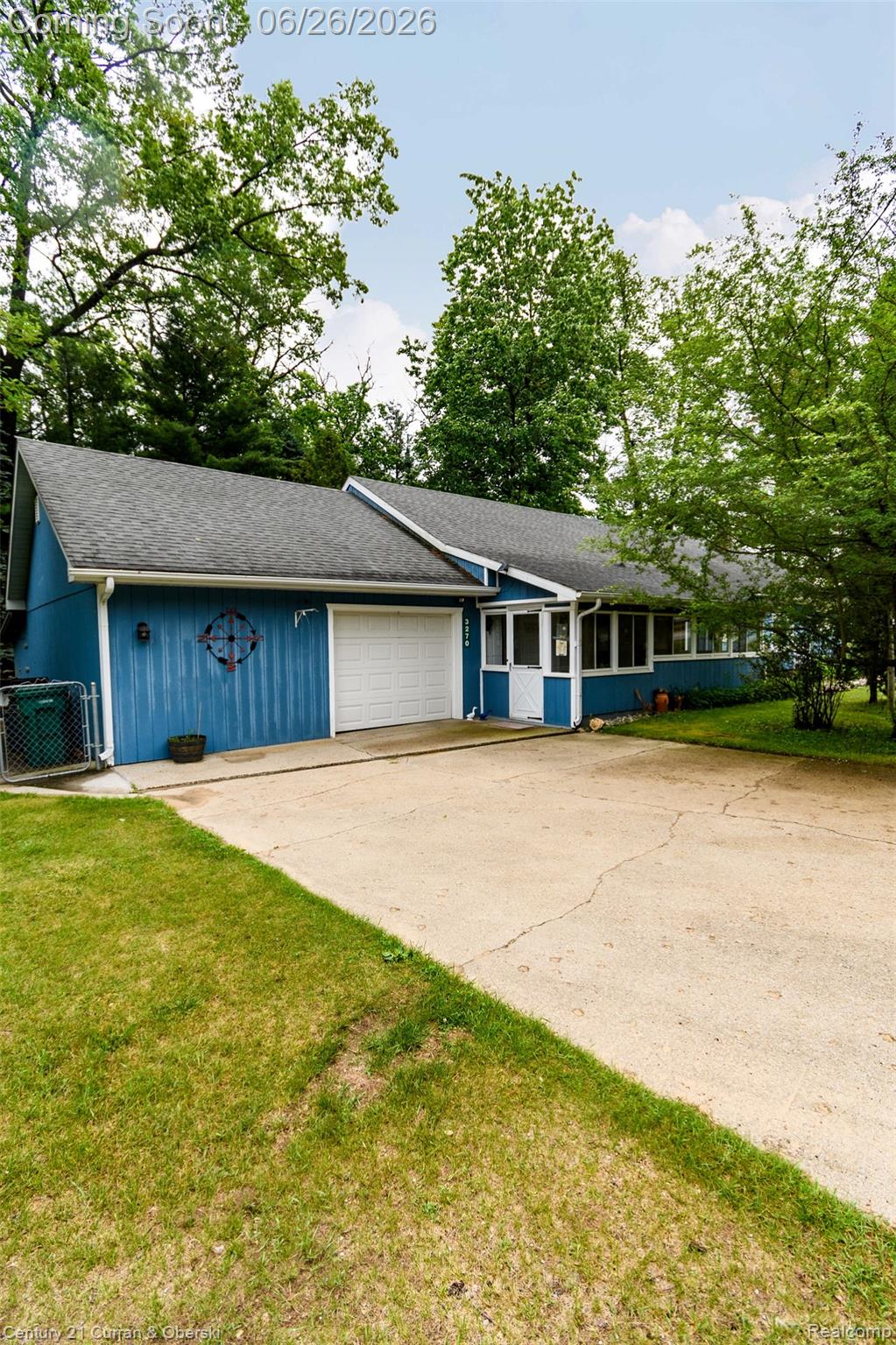 3270 Woods Road Harrison, MI 48625 - Photo 3 of 42 Single-story structure with blue siding, an attached garage, a gray shingle roof, and a concrete driveway