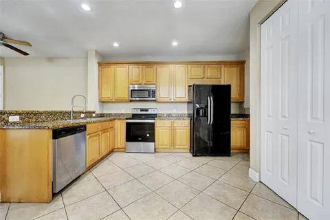 a kitchen with granite countertop a refrigerator and a stove top oven