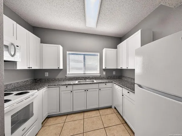 a kitchen with a sink dishwasher and white cabinets with wooden floor
