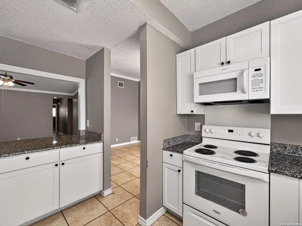 a kitchen with granite countertop white cabinets and white appliances