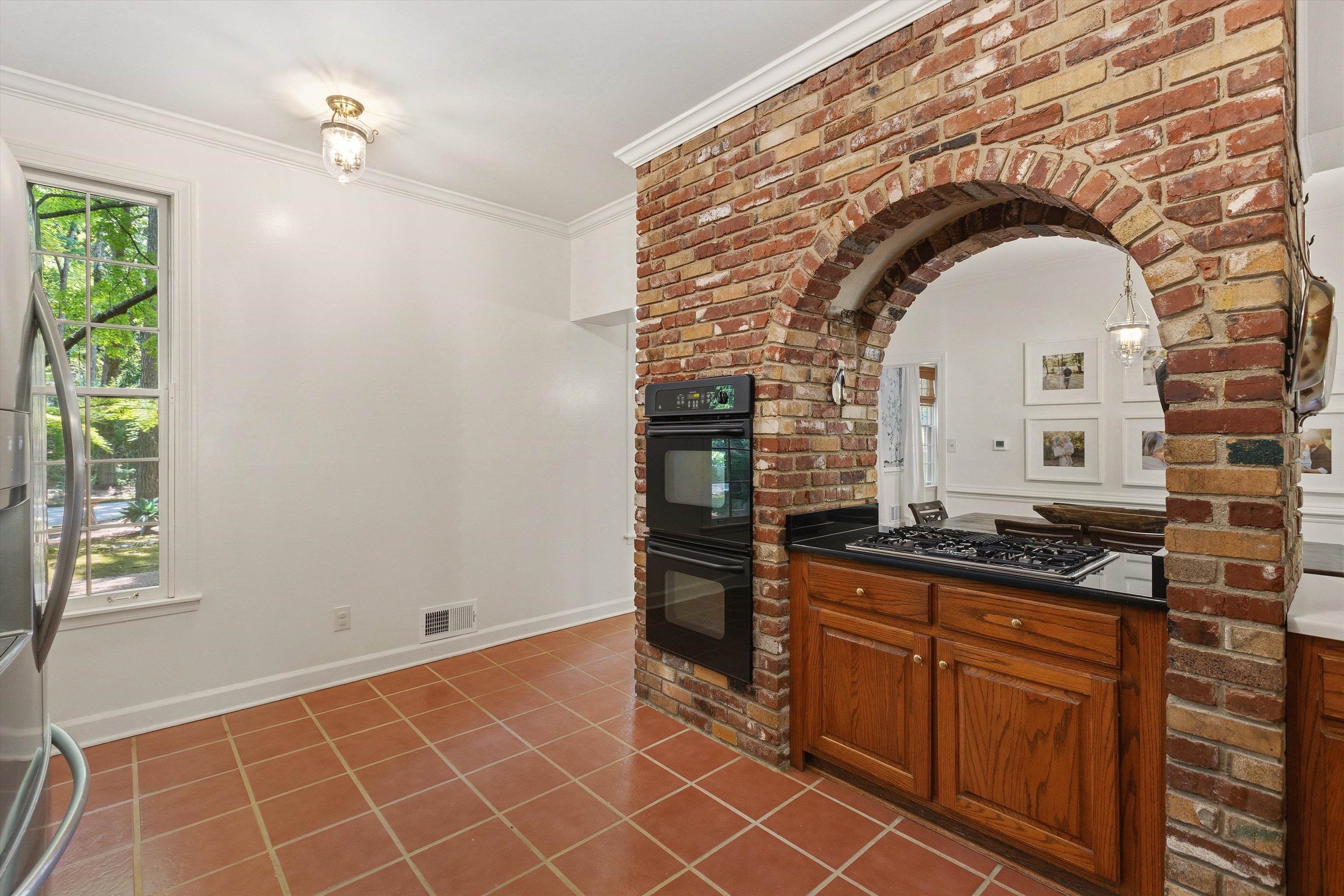 5828 Haymarket Road Memphis, TN 38120 - Photo 16 of 40 Brick archway featuring a built-in cooktop with a black countertop and wood cabinetry