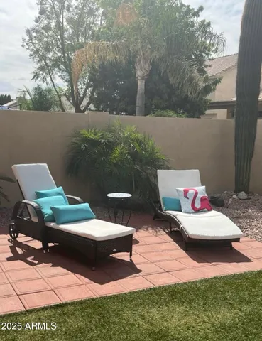 a view of a backyard with couches table and chairs with potted plants