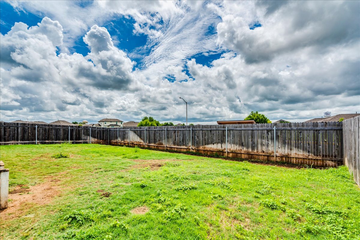 389 Salt Springs Road Kyle, TX 78640 - Photo 25 of 30 Secure backyard provides ample space for recreation and relaxation, enclosed by a robust wood fence.