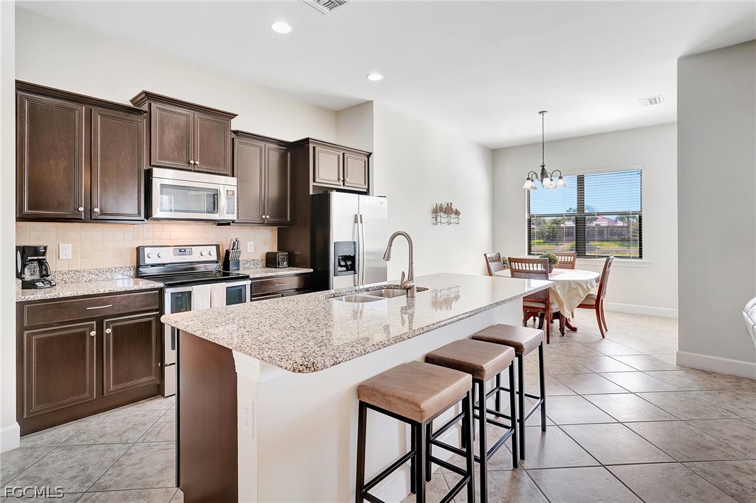 10879 Rutherford Road Fort Myers, FL 33913 - Photo 7 of 36 a kitchen with granite countertop a stove a sink a dining table and chairs