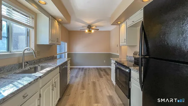 a kitchen with granite countertop a refrigerator a sink and dishwasher