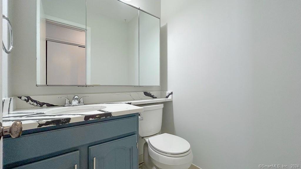 8 Derby Court, Unit 8 Brookfield, CT 06804 - Photo 19 of 26 a bathroom with a granite countertop toilet sink and mirror