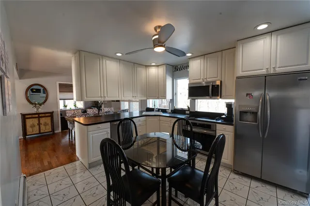 a kitchen with kitchen island granite countertop a refrigerator a stove a microwave oven a sink a dining table and chairs with wooden floor