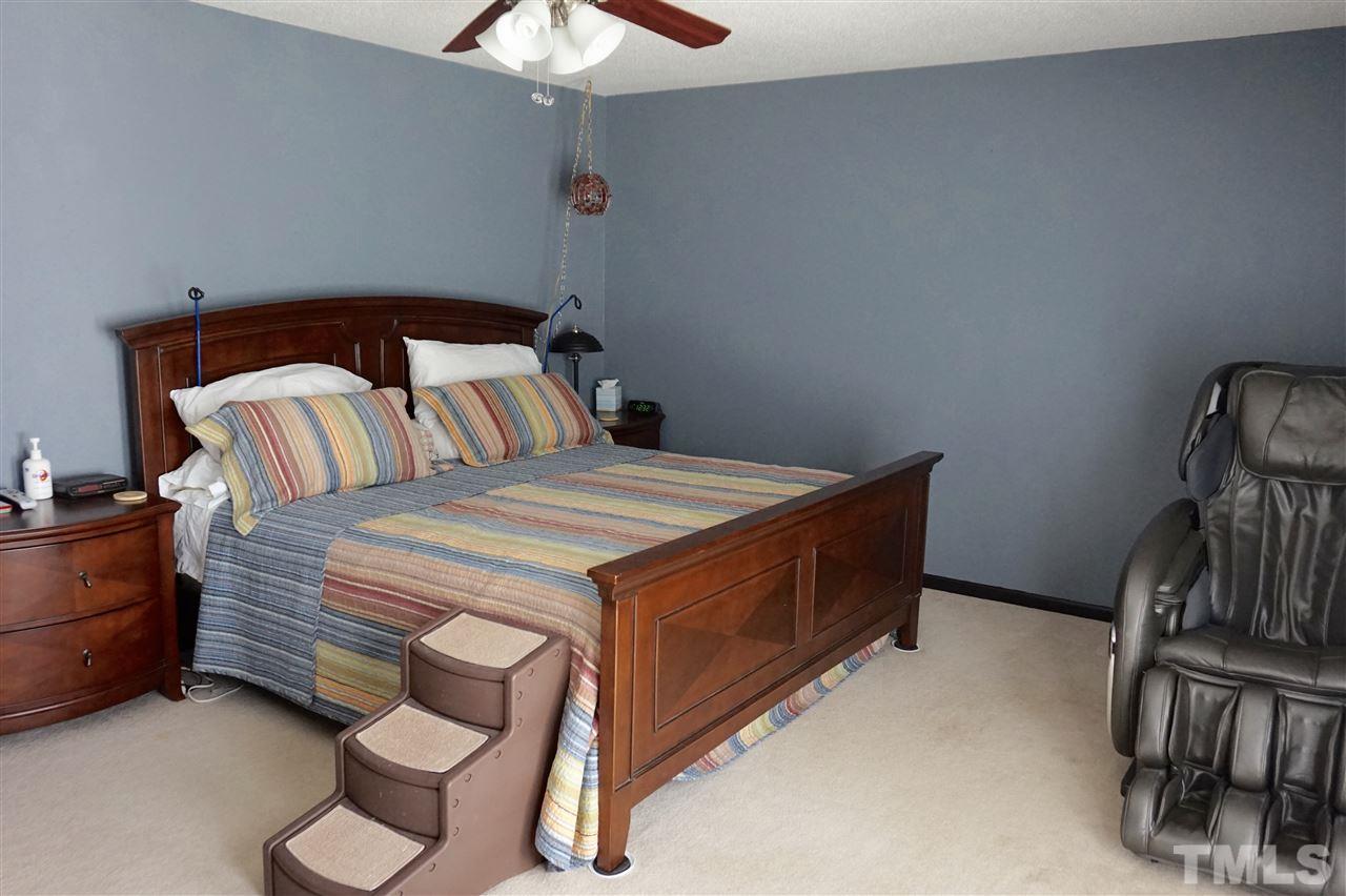 8605 Maidstone Court Raleigh, NC 27613 - Photo 7 of 13 a bedroom with a bed and a chandelier
