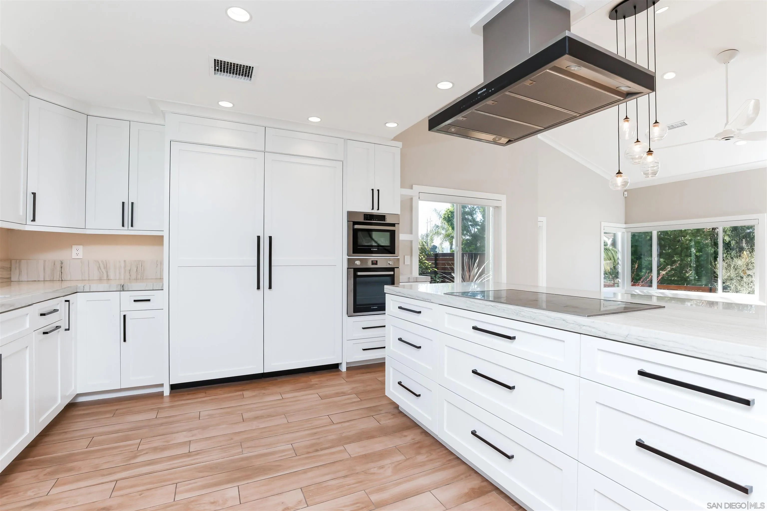 2102 Wandering Road Encinitas, CA 92024 - Photo 9 of 37 a kitchen with stainless steel appliances kitchen island granite countertop white cabinets and window