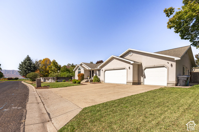1143 East Mountain Road Logan, UT 84321 - Photo 46 of 64 Stucco exterior with a pitched roof, attached two-car garage, concrete driveway, and established landscaping