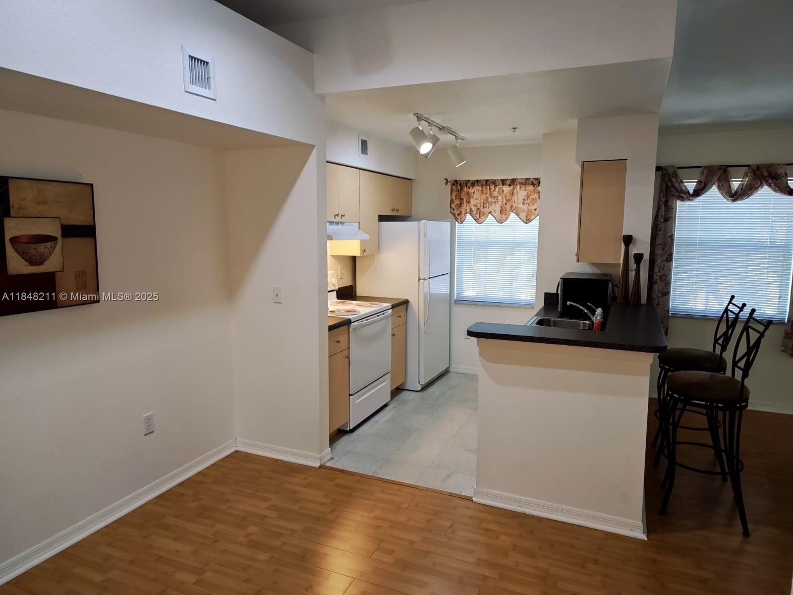 2586 Centergate Drive, Unit 307 Miramar, FL 33025 - Photo 12 of 43 a kitchen with white cabinets and black appliances