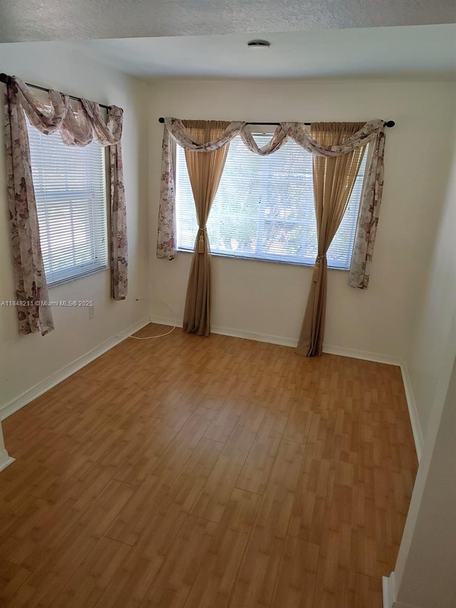 2586 Centergate Drive, Unit 307 Miramar, FL 33025 - Photo 15 of 43 a view of an empty room with wooden floor and a window
