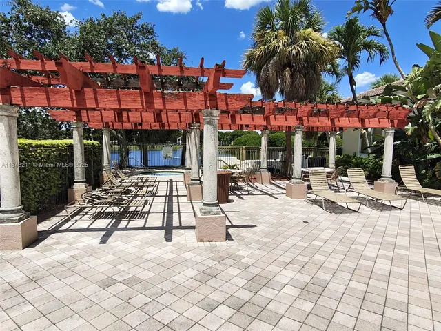 a view of a patio with a table and chairs under an umbrella with palm trees
