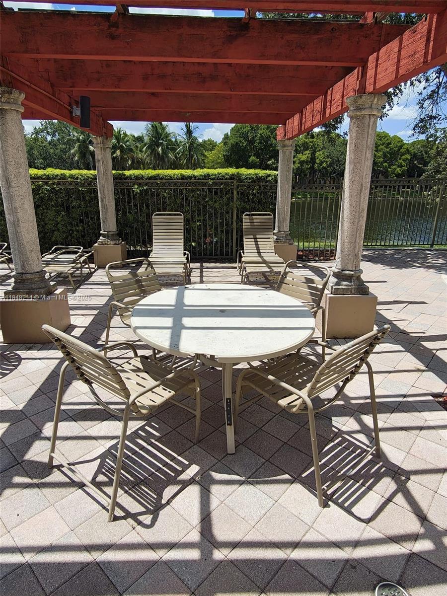2586 Centergate Drive, Unit 307 Miramar, FL 33025 - Photo 39 of 43 a view of patio with table and chairs under an umbrella
