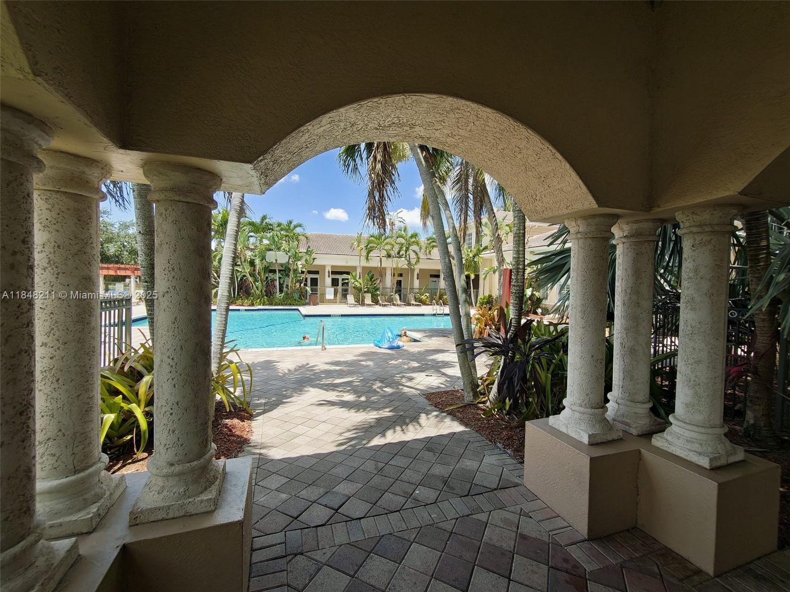 2586 Centergate Drive, Unit 307 Miramar, FL 33025 - Photo 41 of 43 a view of a porch with a table and chairs under an umbrella