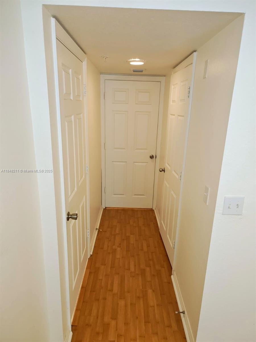 2586 Centergate Drive, Unit 307 Miramar, FL 33025 - Photo 7 of 43 a view of a hallway with wooden floor and a bathroom