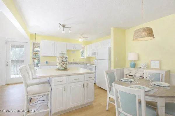 a kitchen with a refrigerator a stove a sink and white cabinets with wooden floor