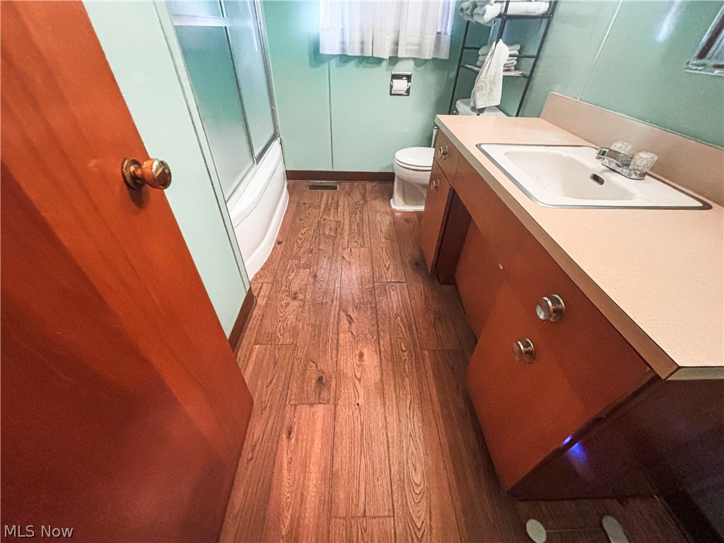 724 East Main Street Barnesville, OH 43713 - Photo 16 of 28 Bathroom with vanity, dark wood-style floors, and enclosed tub / shower combo