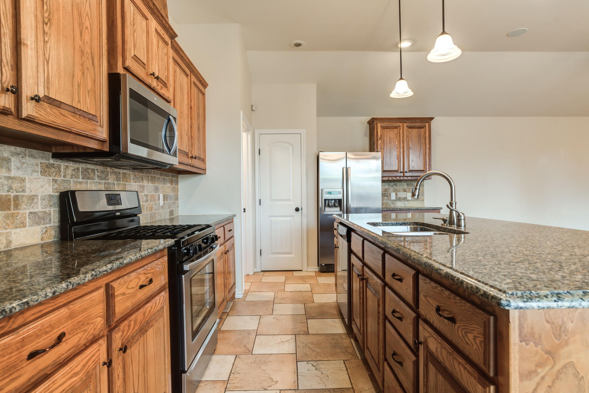 4802 Amherst Street Lubbock, TX 79416 - Photo 12 of 33 a kitchen with stainless steel appliances granite countertop a stove a sink and a microwave