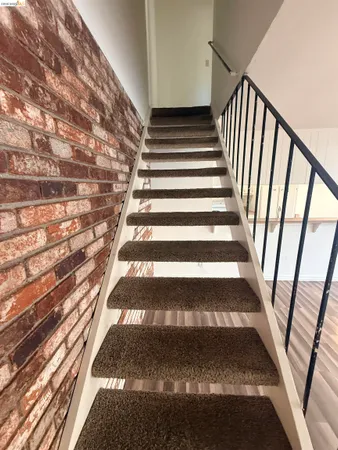 a view of staircase with white walls and a rug