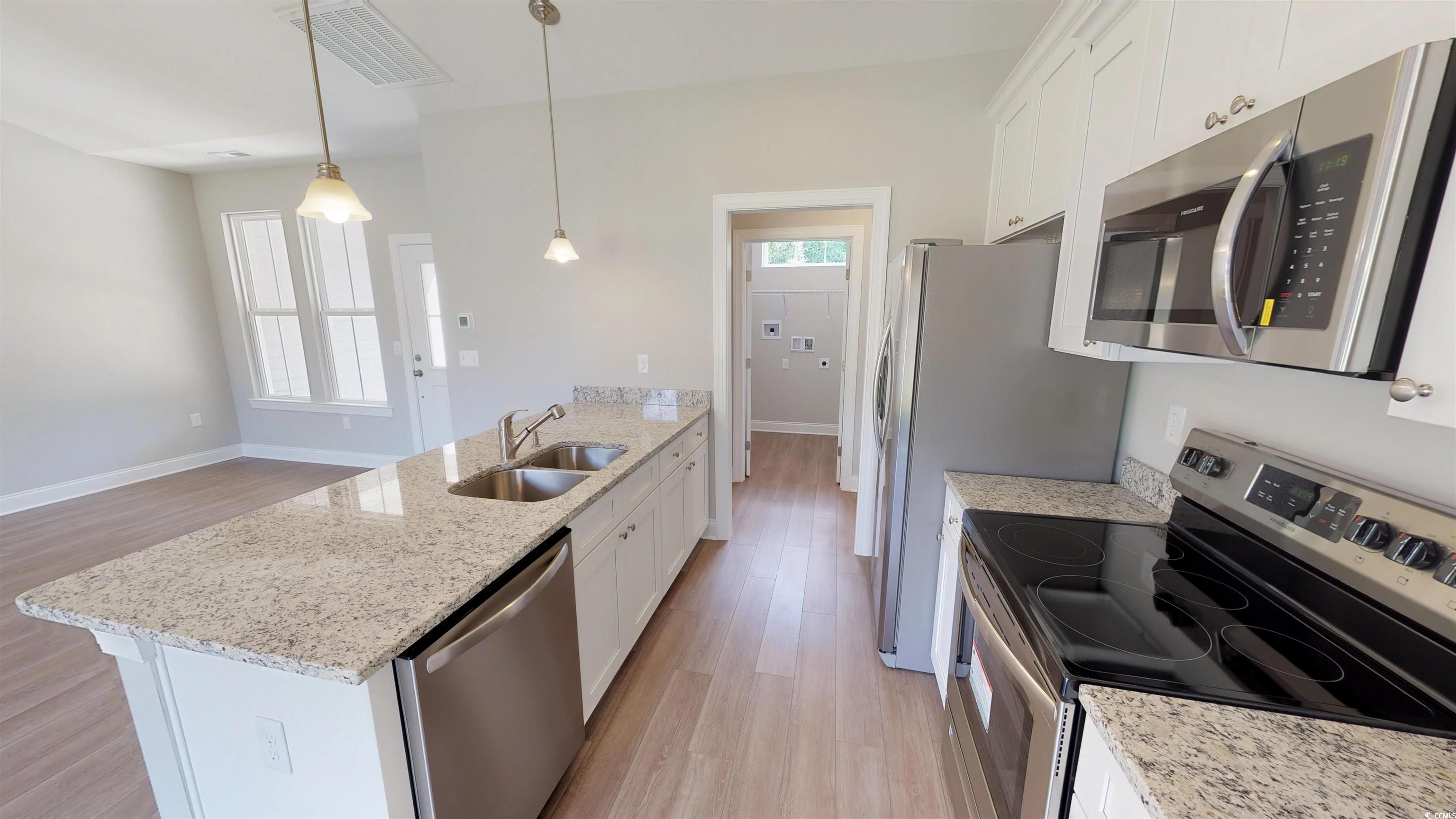 29 Wimbledon Court, Unit WVC 8 Pawleys Island, SC 29585 - Photo 5 of 12 Kitchen with light wood-style flooring, stainless steel appliances, a peninsula, decorative light fixtures, and light stone countertops