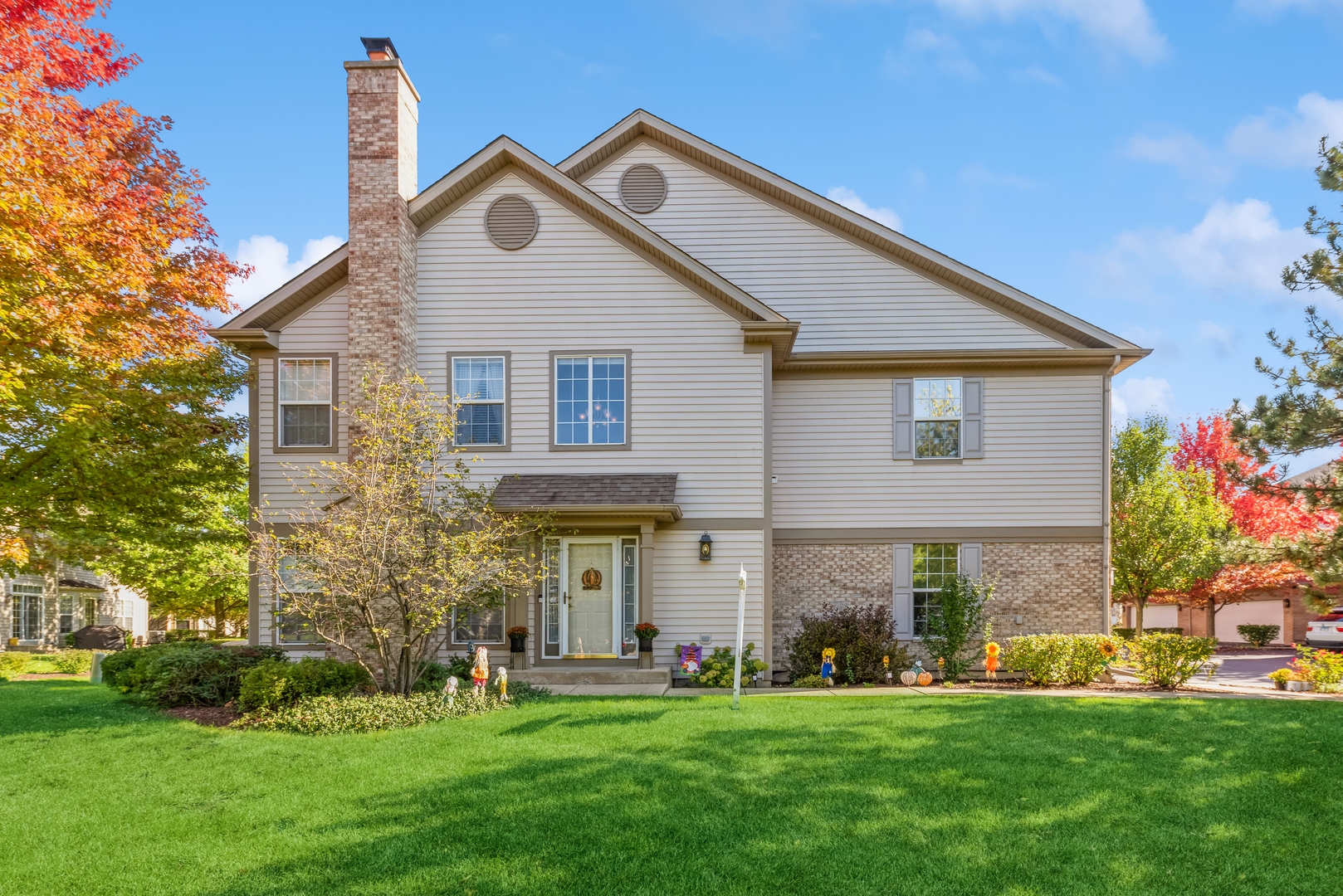 a front view of a house with a garden and trees