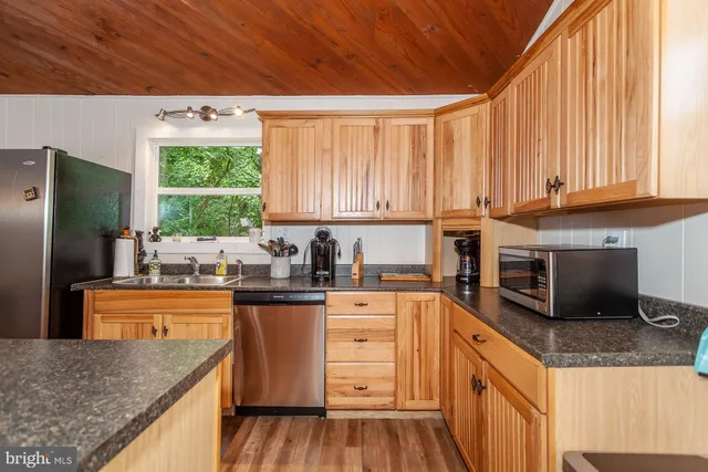 a kitchen with stainless steel appliances granite countertop a stove a sink dishwasher and a refrigerator with wooden cabinets
