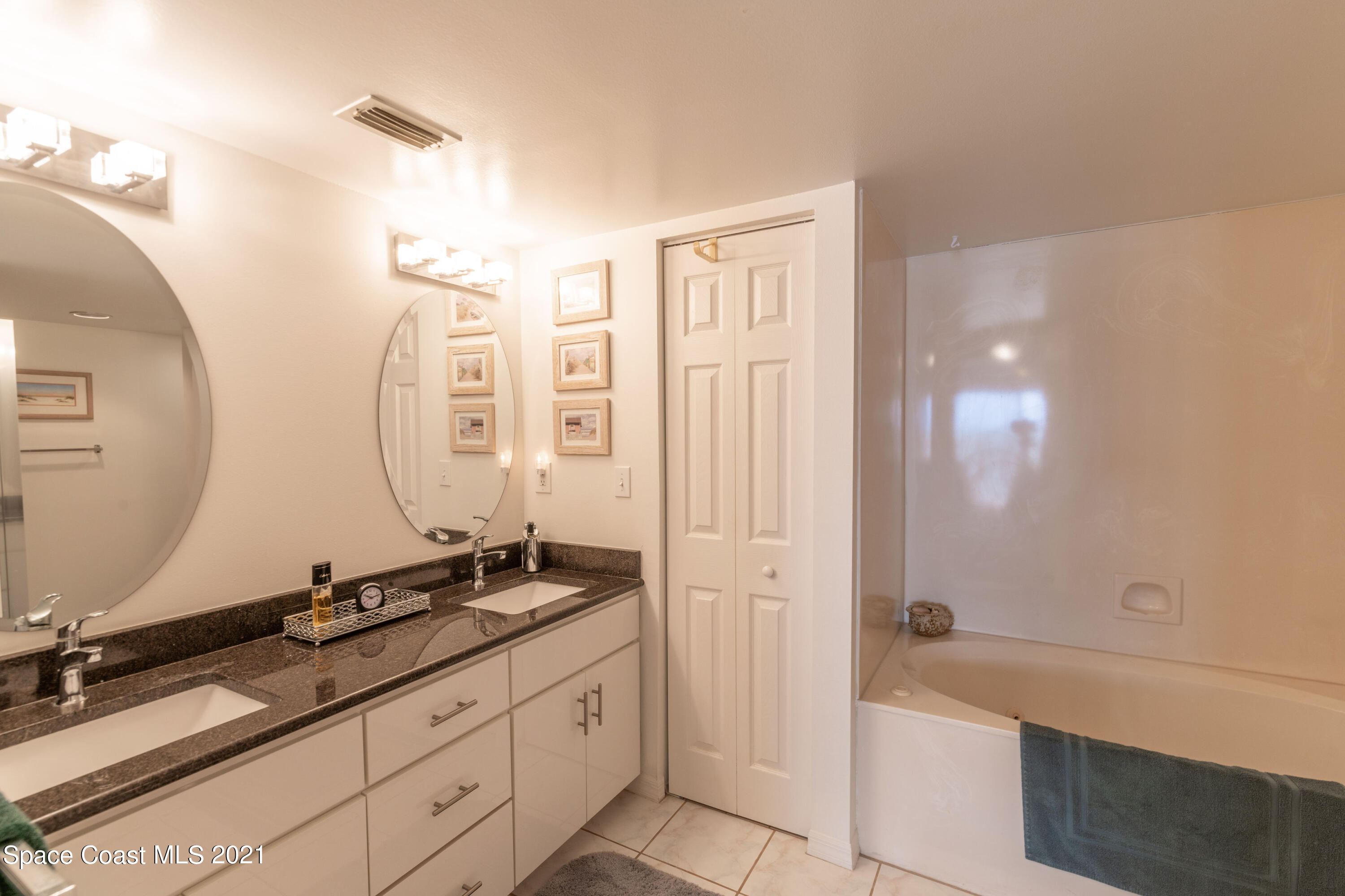 6770 Ridgewood Avenue, Unit 1002 Cocoa Beach, FL 32931 - Photo 13 of 16 a spacious bathroom with a granite countertop sink a mirror and a bathtub