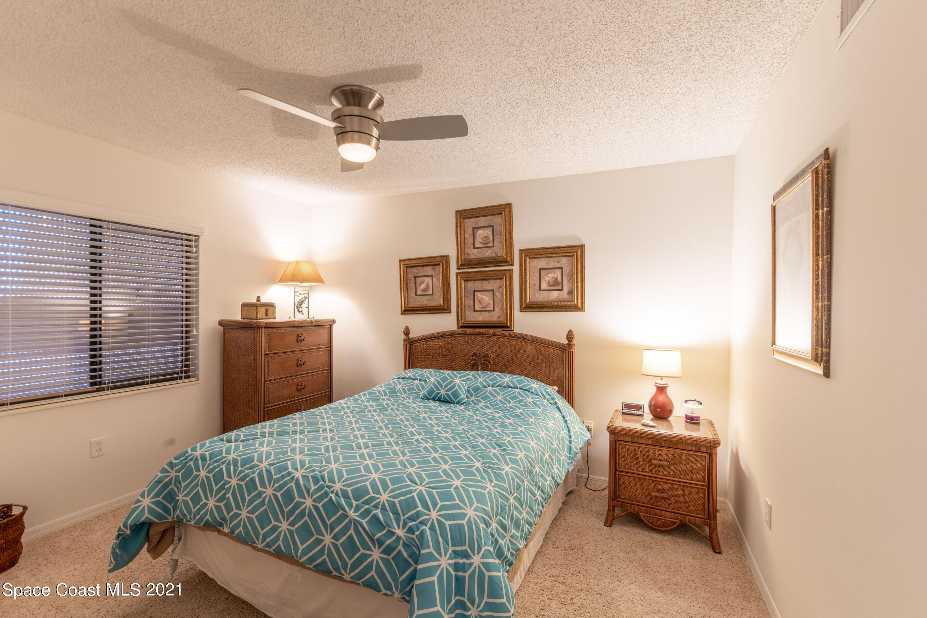 6770 Ridgewood Avenue, Unit 1002 Cocoa Beach, FL 32931 - Photo 15 of 16 a bedroom with a large bed and a chandelier