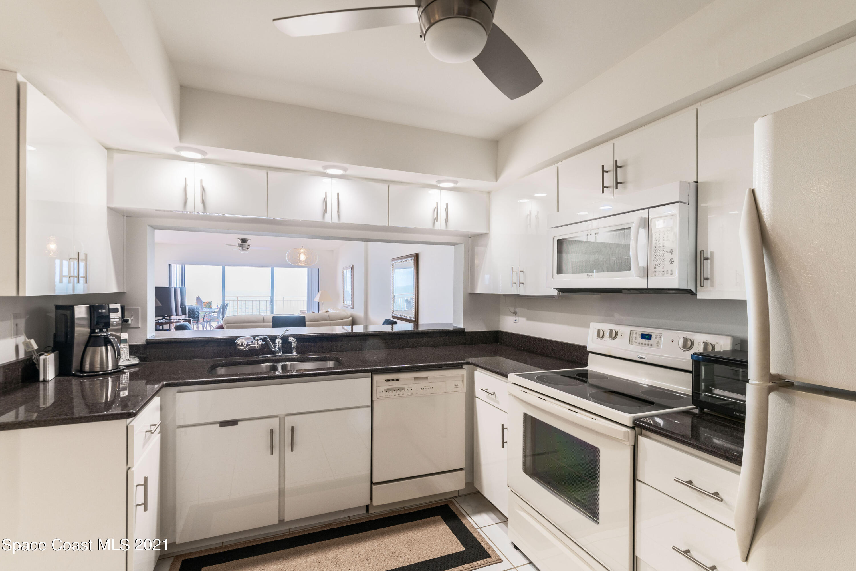 6770 Ridgewood Avenue, Unit 1002 Cocoa Beach, FL 32931 - Photo 9 of 16 a kitchen with granite countertop a sink stainless steel appliances and white cabinets
