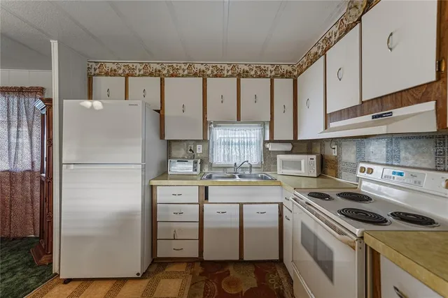 a kitchen with a refrigerator sink and cabinets