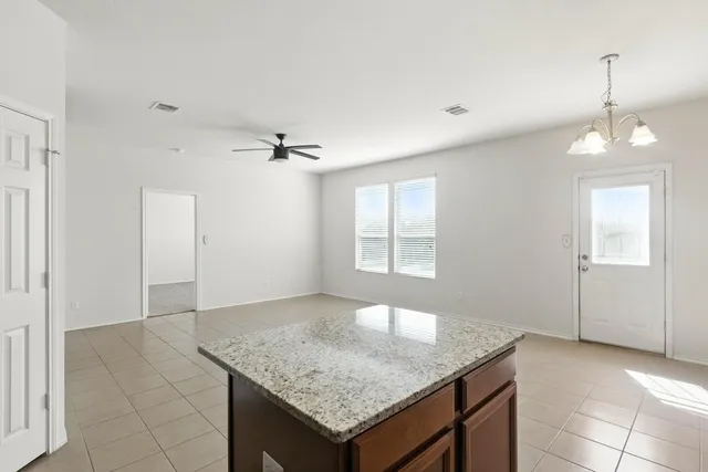 an empty room with a granite counter top and a chandelier