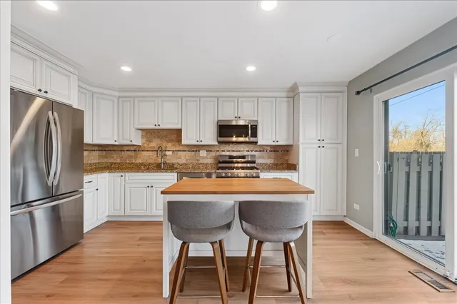 a kitchen with stainless steel appliances granite countertop a refrigerator a stove a sink dishwasher and a refrigerator with wooden floor