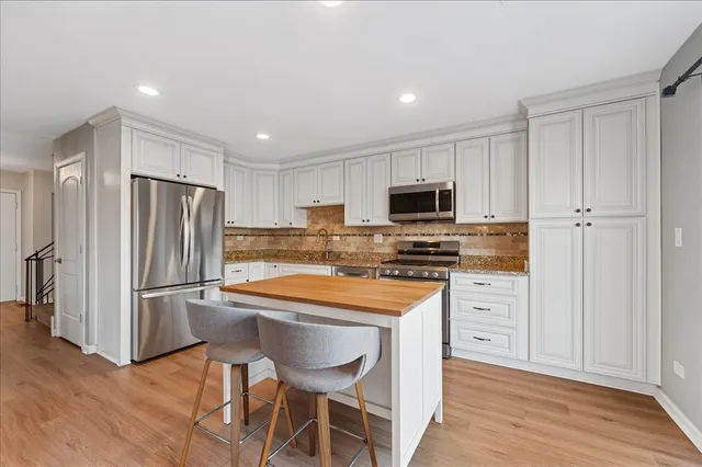 a kitchen with stainless steel appliances a refrigerator stove microwave and white cabinets