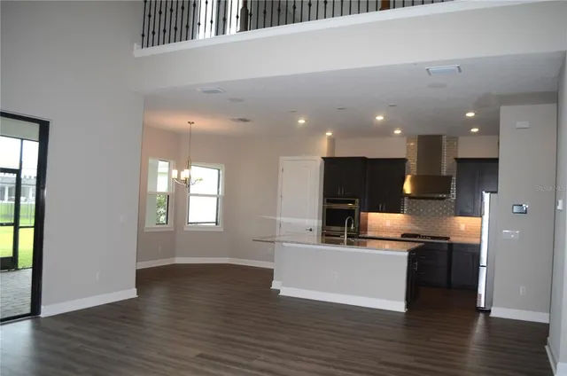 a large kitchen with stainless steel appliances a large counter top a stove and a refrigerator