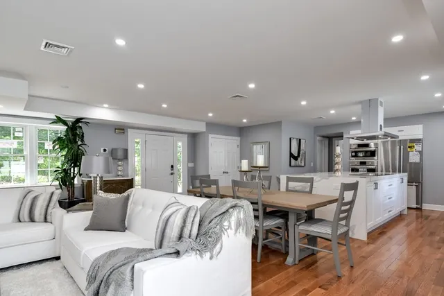 a living room with furniture a wooden floor and kitchen view