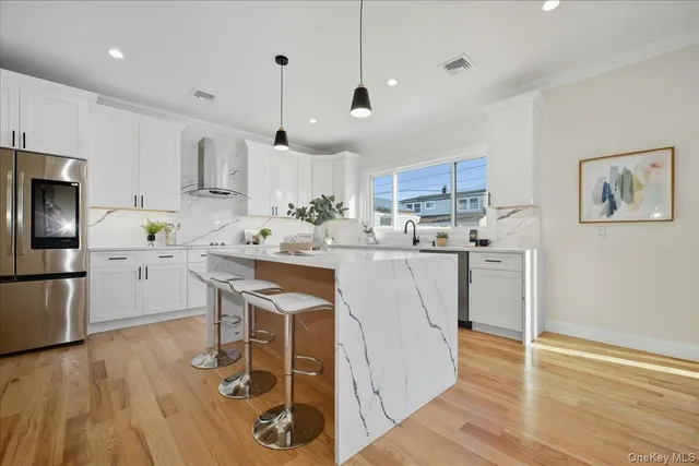 a kitchen with stainless steel appliances kitchen island granite countertop a table chairs refrigerator and microwave