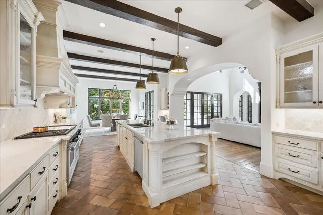 a large white kitchen with granite countertop a large window and white cabinets