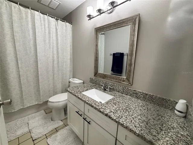 a bathroom with a granite countertop sink and a mirror with toilet